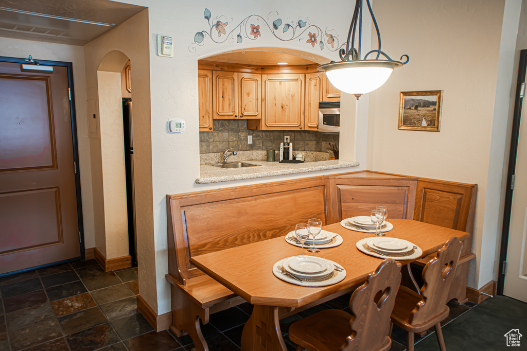 Kitchen featuring arched walkways, light countertops, tasteful backsplash, stainless steel microwave, and decorative light fixtures
