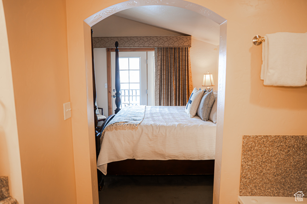 Bedroom with access to exterior, arched walkways, and vaulted ceiling