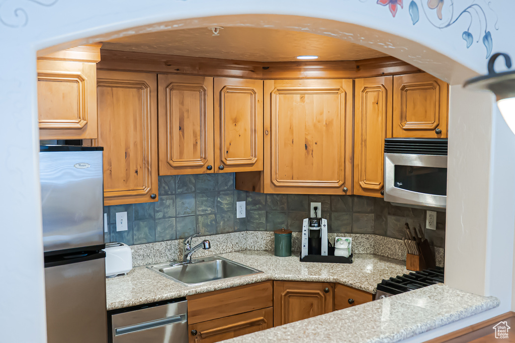 Kitchen featuring stainless steel appliances, tasteful backsplash, a sink, and brown cabinets