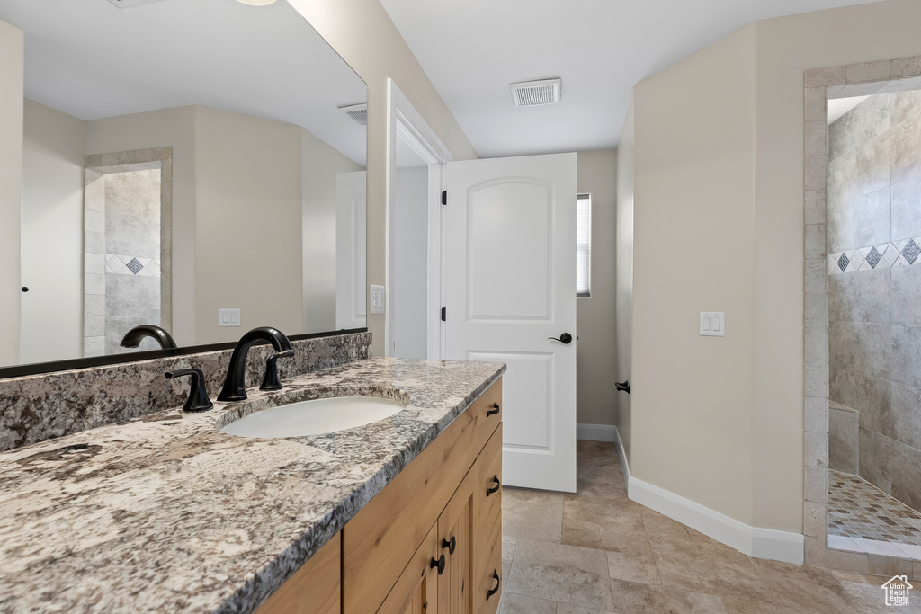 Bathroom with visible vents, vanity, baseboards, and a walk in shower