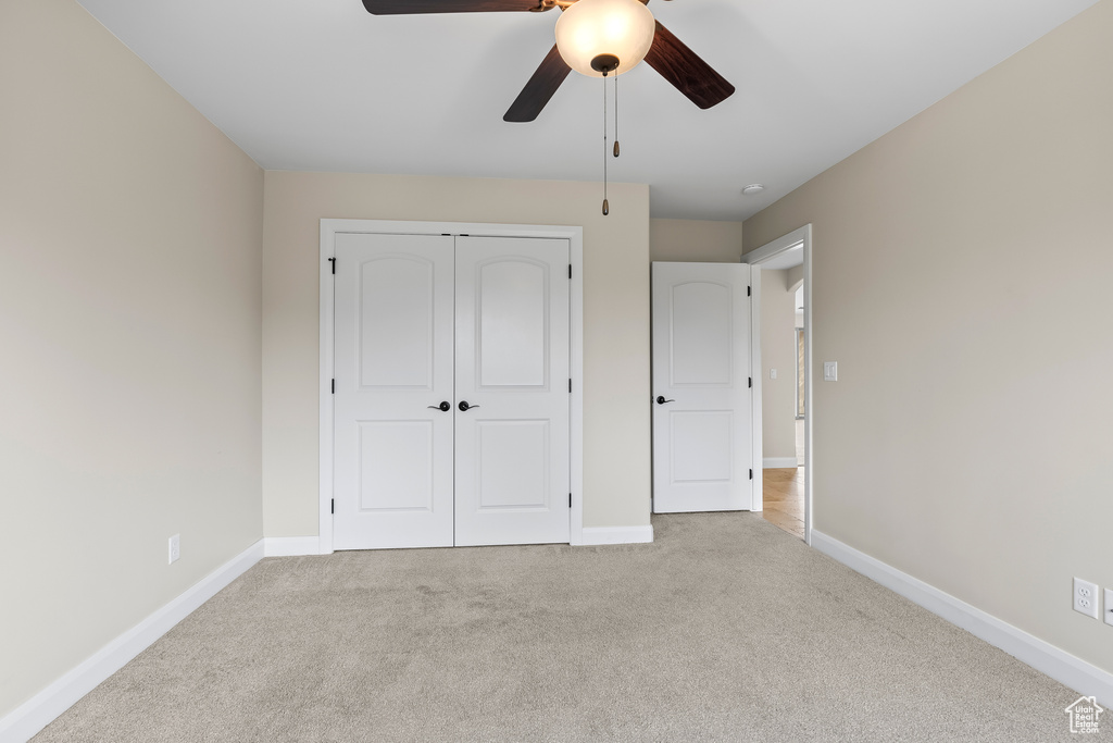 Unfurnished bedroom with light carpet, a ceiling fan, baseboards, and a closet