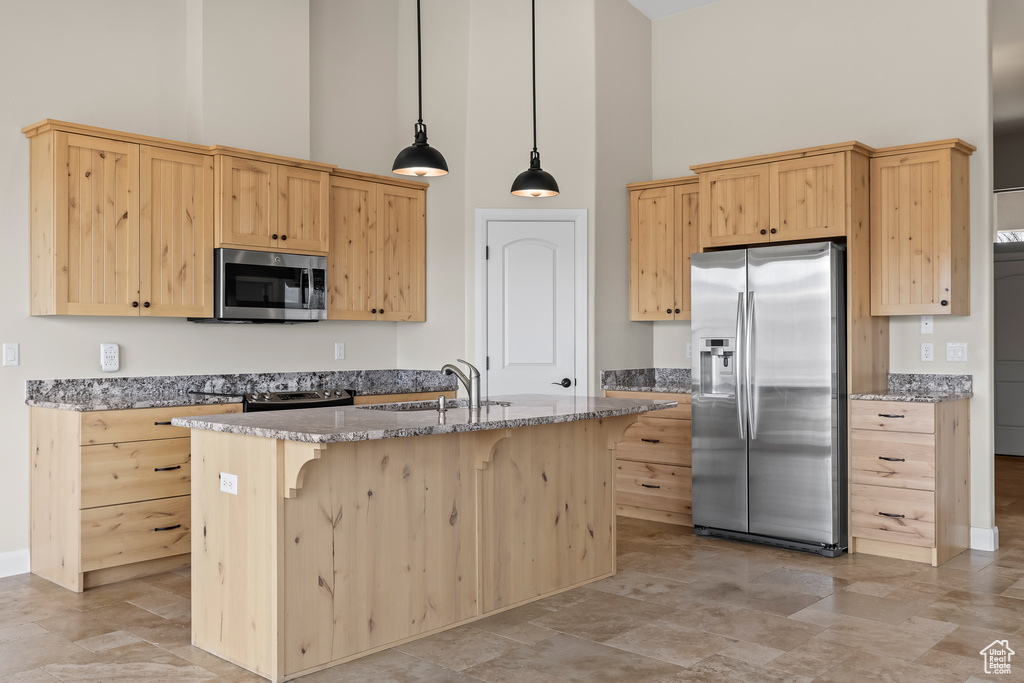 Kitchen with stainless steel appliances, a sink, an island with sink, and light brown cabinetry