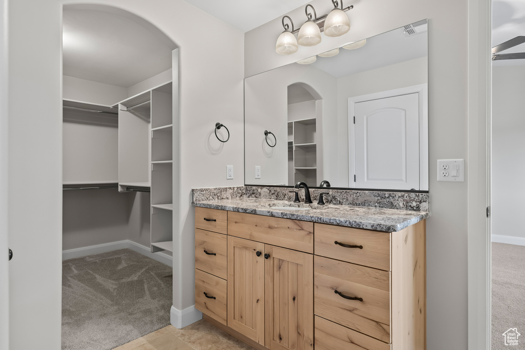 Bathroom with a walk in closet, vanity, and baseboards