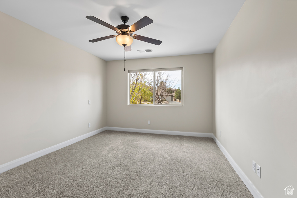 Unfurnished room featuring a ceiling fan, carpet, visible vents, and baseboards