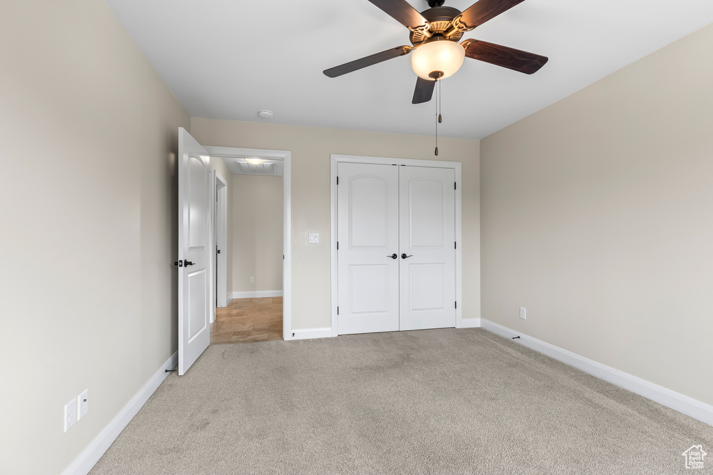 Unfurnished bedroom featuring a ceiling fan, a closet, light carpet, and baseboards