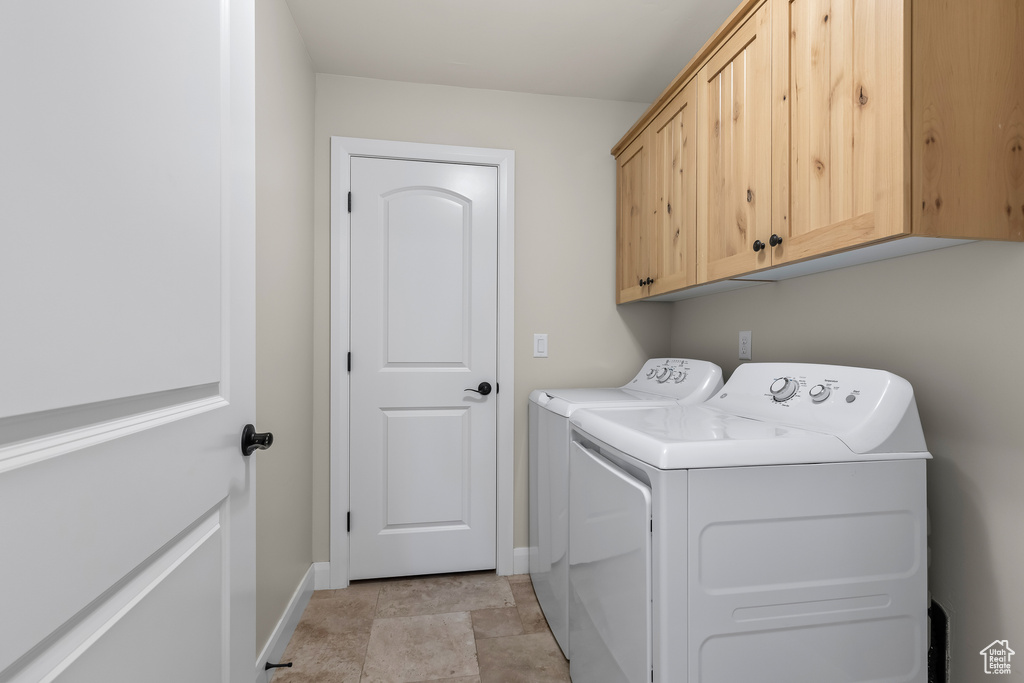 Washroom featuring baseboards, cabinet space, and washing machine and clothes dryer