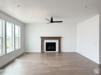 Unfurnished living room with a ceiling fan, wood finished floors, baseboards, and a fireplace