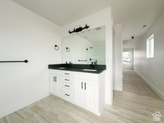 Bathroom featuring double vanity, wood finished floors, and baseboards