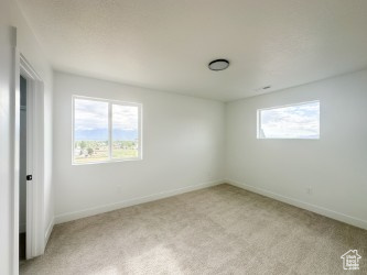 Empty room with light colored carpet and baseboards