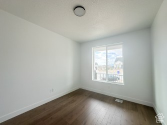 Unfurnished room with baseboards and dark wood-style flooring
