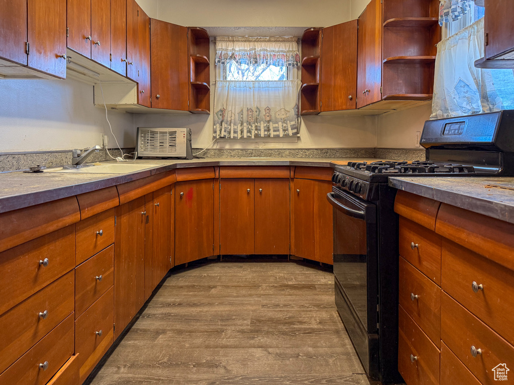 Kitchen with a sink, light countertops, open shelves, light wood finished floors, and gas stove