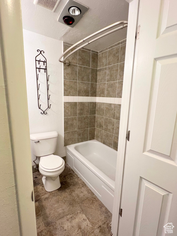 Bathroom with a textured ceiling, toilet, and shower / bathtub combination