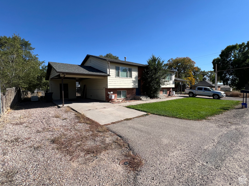 Tri-level home with brick siding, driveway, a front lawn, and fence