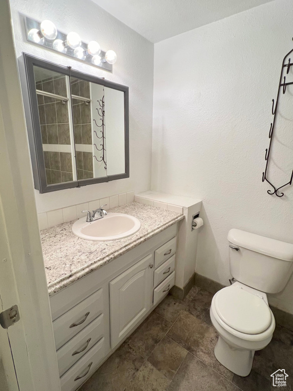 Bathroom featuring toilet, baseboards, and vanity
