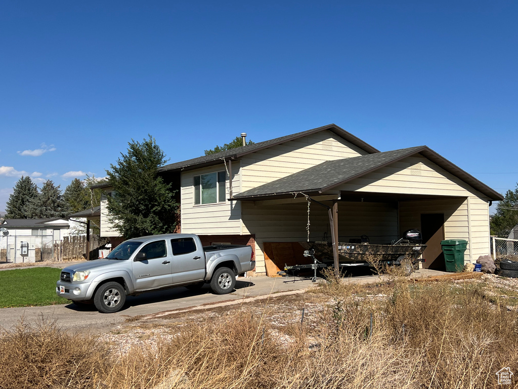 Exterior space with driveway and a shingled roof