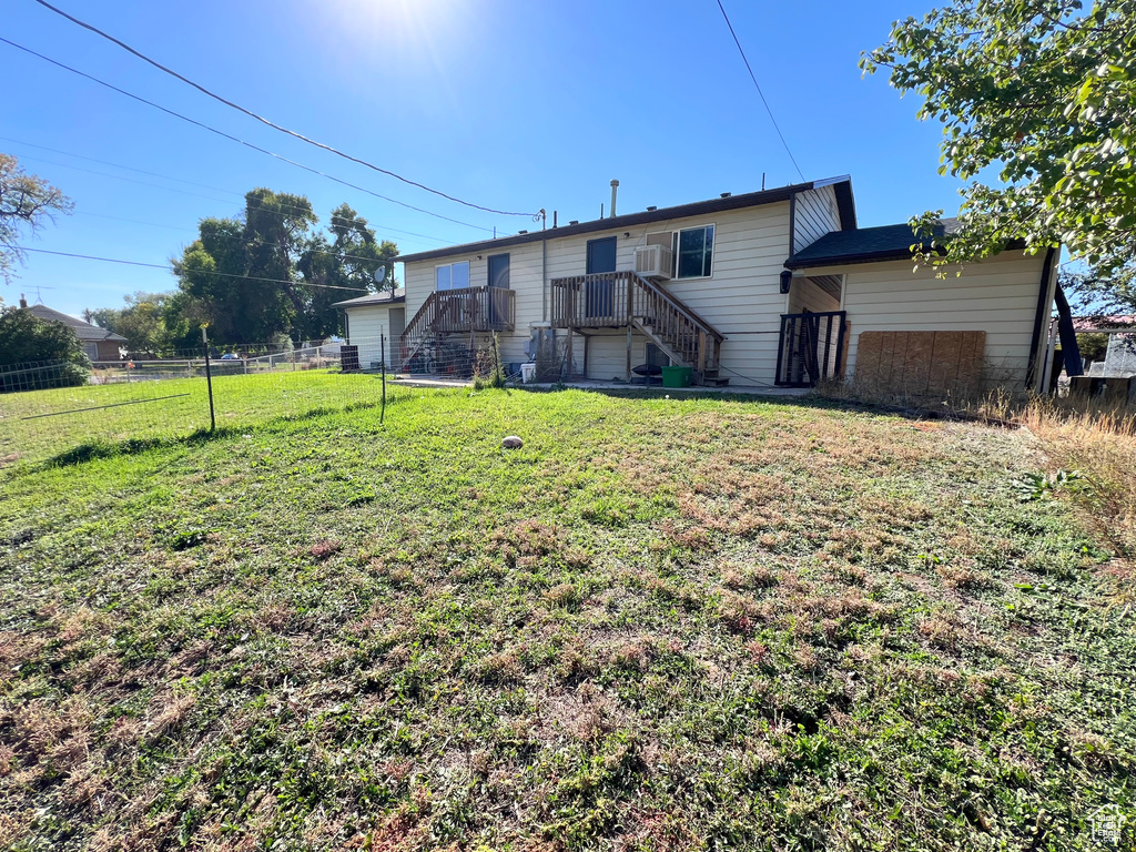 Back of property featuring stairs, fence, and a lawn