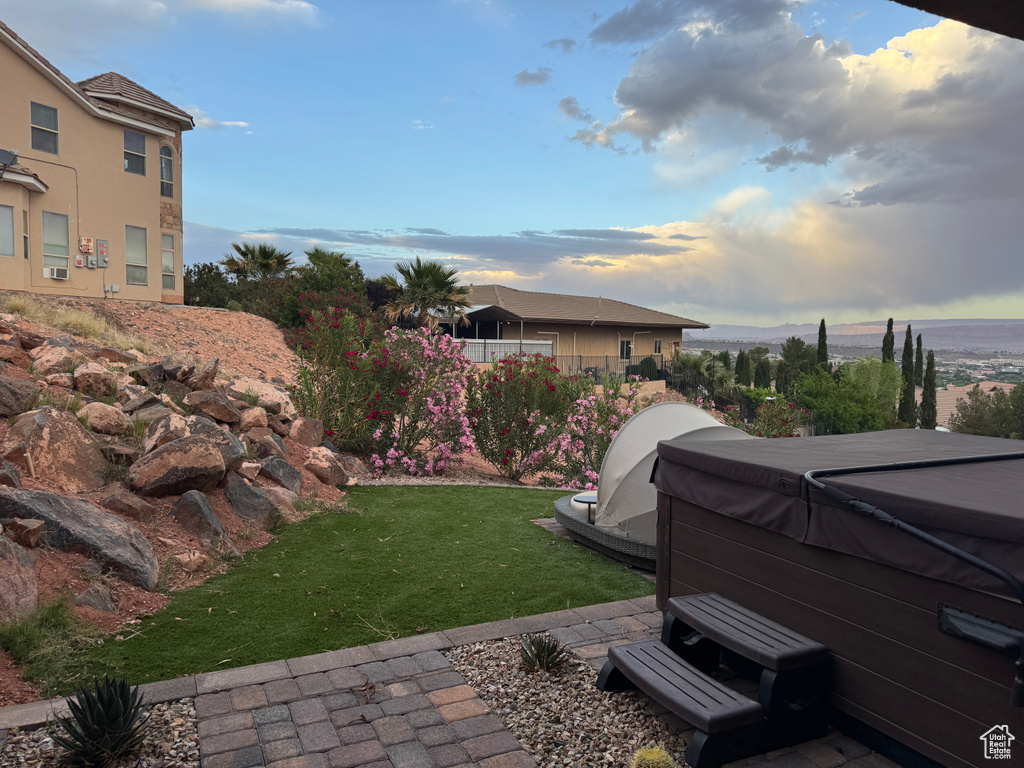 Yard at dusk featuring a hot tub and a yard