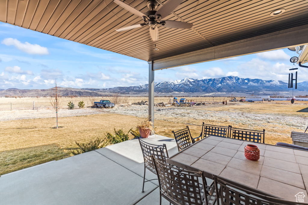 View of patio with outdoor dining area, a mountain view, and ceiling fan