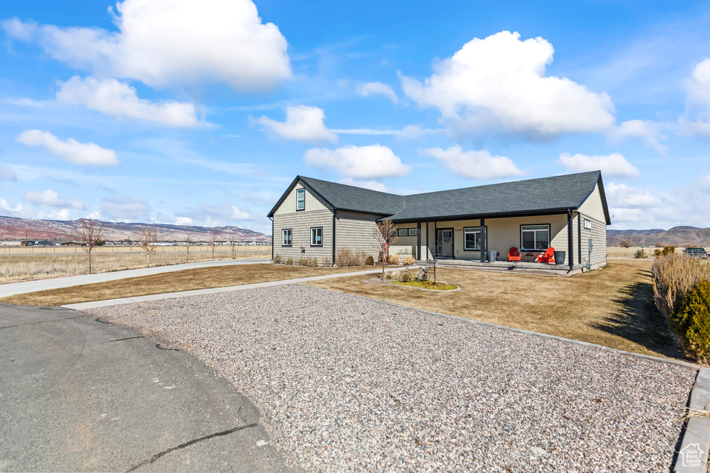 View of front facade with gravel driveway, a shingled roof, and a mountain view