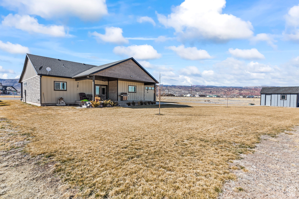View of front of house with a front lawn, board and batten siding, an outdoor structure, and a shingled roof