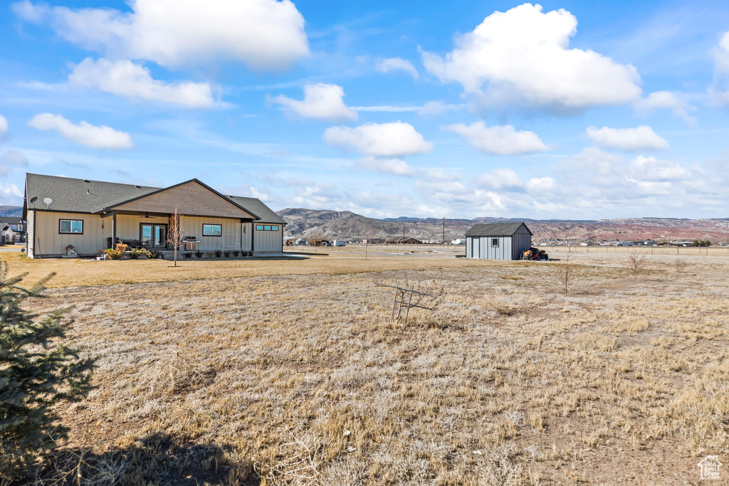 View of yard featuring a rural view, an outbuilding, a storage unit, a mountain view, and a porch