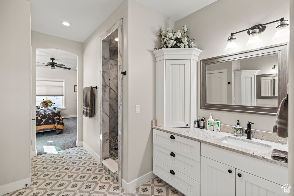 Ensuite bathroom with ceiling fan, connected bathroom, vanity, baseboards, and a stall shower