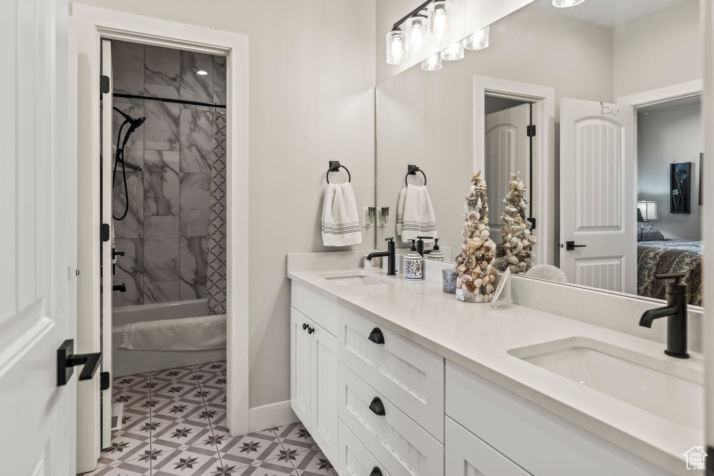 Bathroom featuring baseboards, a sink, ensuite bath, and double vanity