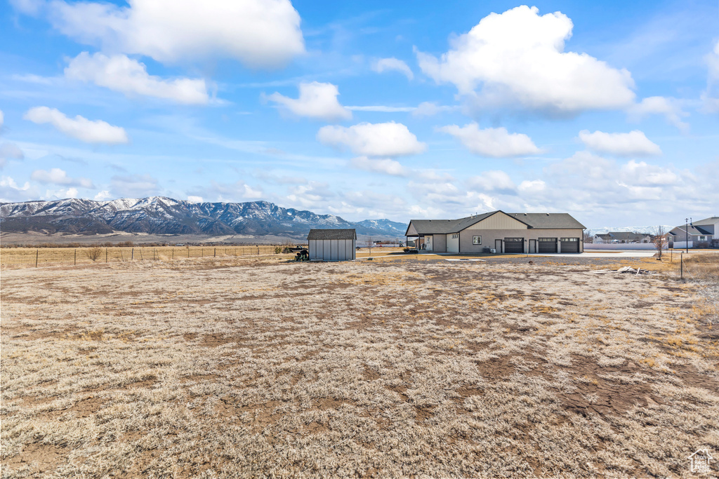 View of yard with a rural view, a storage unit, a mountain view, and an outbuilding