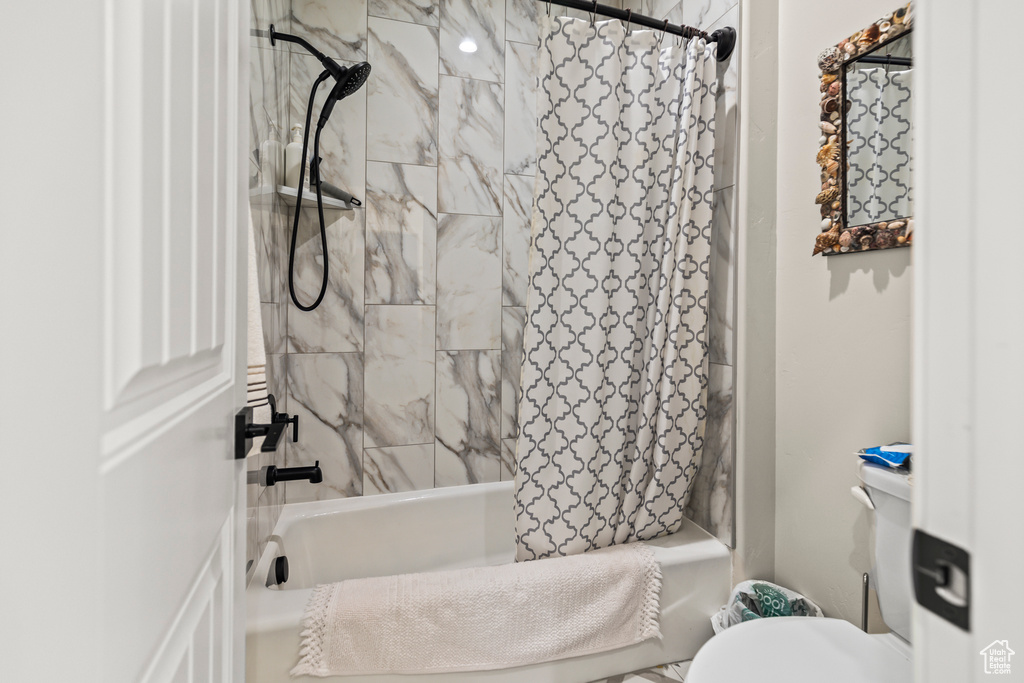 Full bathroom featuring toilet and shower / tub combo with curtain