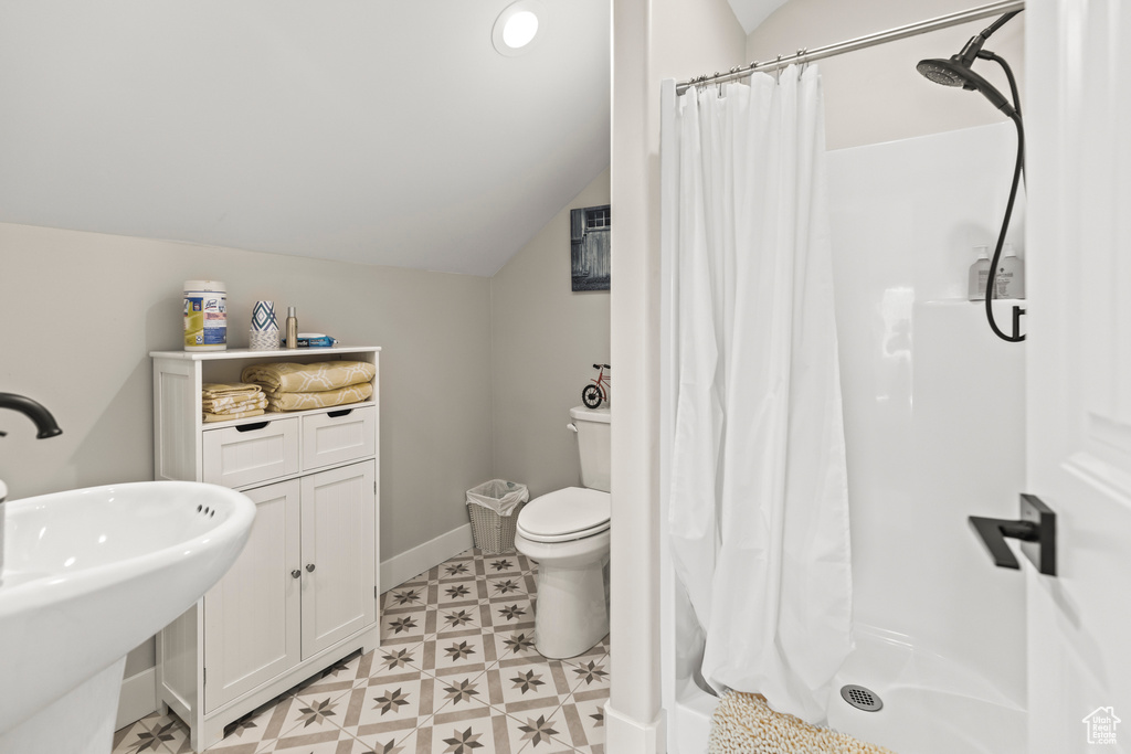 Bathroom with lofted ceiling, a stall shower, and toilet
