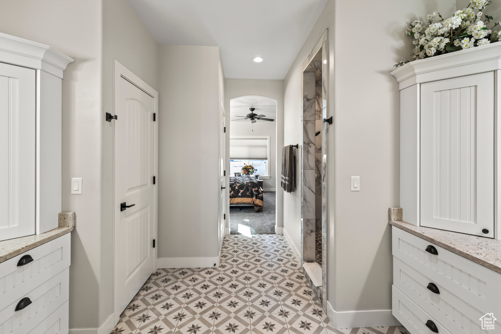 Corridor featuring light floors, baseboards, and arched walkways