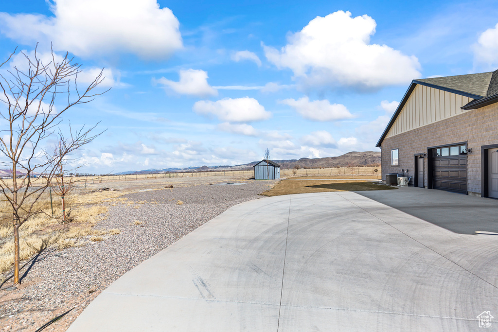 View of yard featuring a garage, a storage unit, a mountain view, and concrete driveway