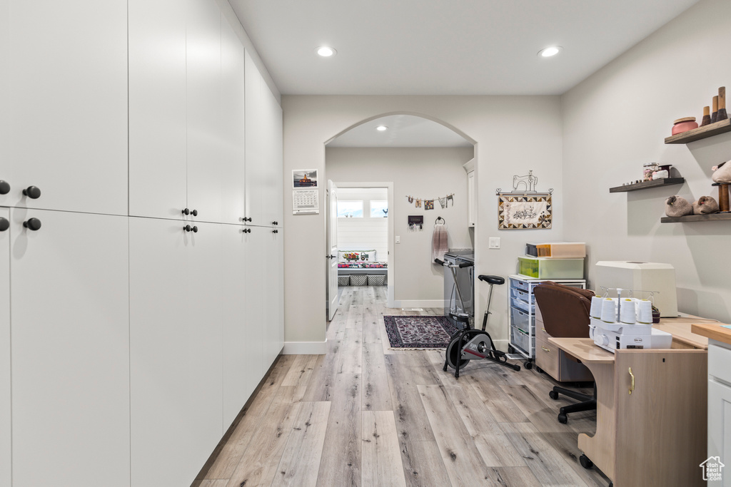 Home office with arched walkways, baseboards, light wood finished floors, and recessed lighting
