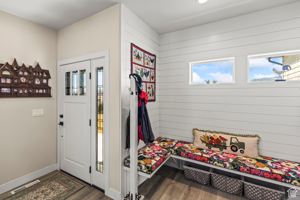 Foyer featuring wood walls, wood finished floors, visible vents, and baseboards