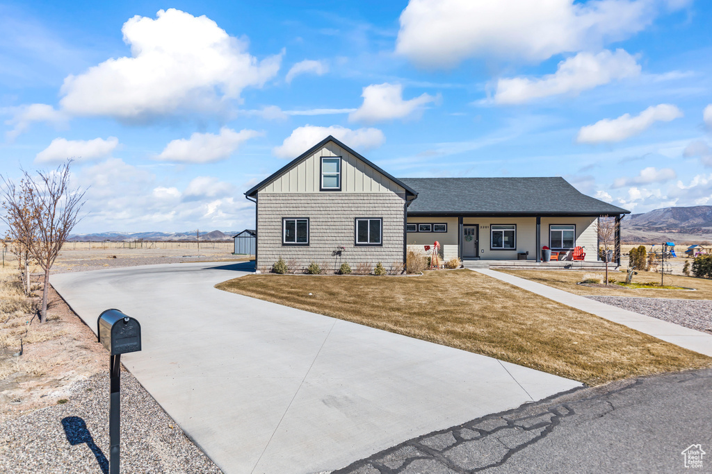 View of front facade with driveway, a mountain view, a porch, board and batten siding, and a front yard