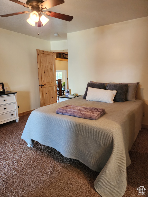 Bedroom with a ceiling fan and dark colored carpet
