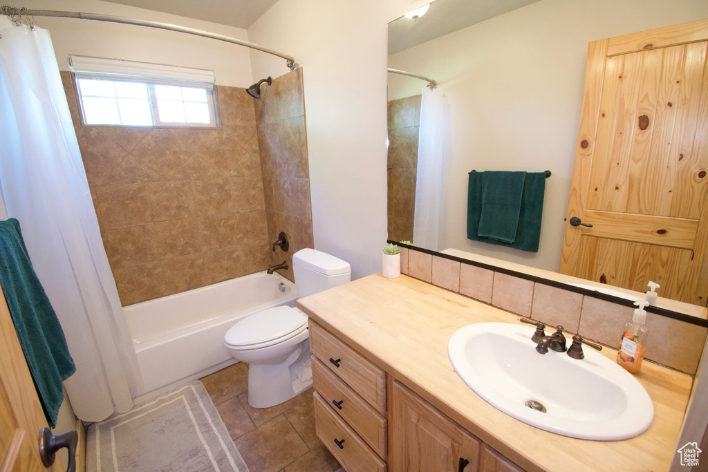 Bathroom with tile patterned floors, vanity, toilet, and shower / tub combo with curtain