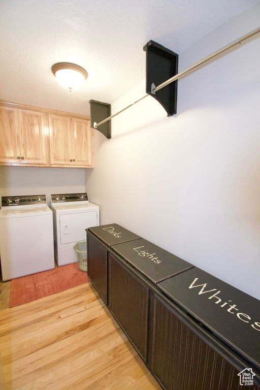 Laundry area featuring light wood finished floors, separate washer and dryer, and cabinet space