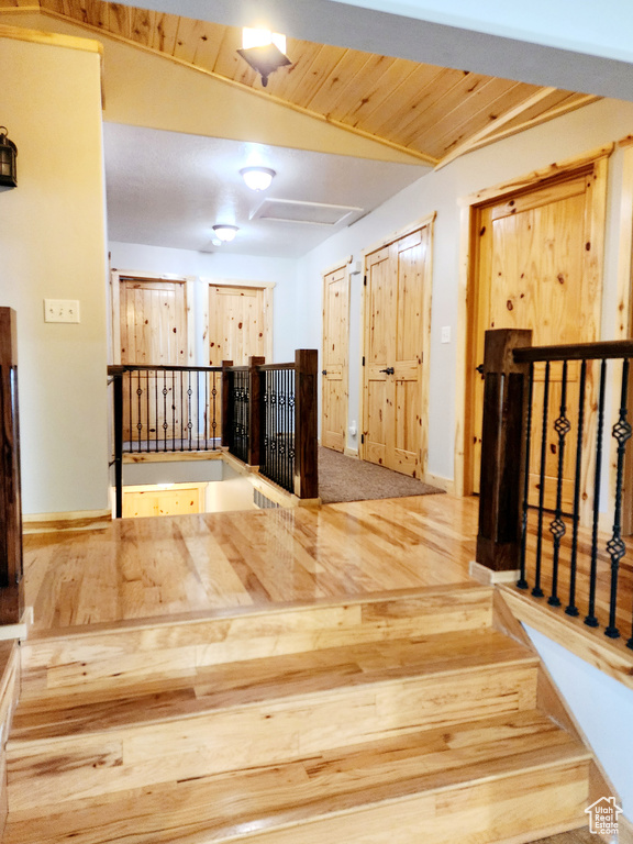 Interior space with wooden ceiling, attic access, and an upstairs landing