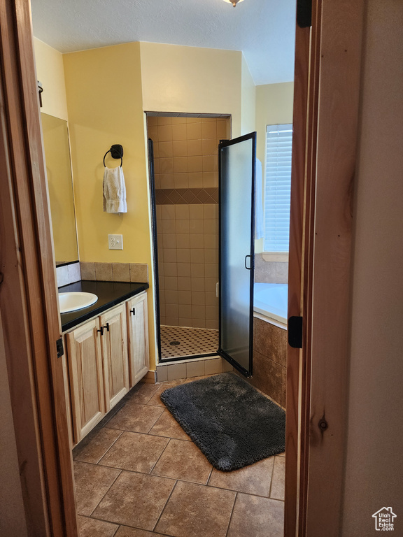 Bathroom featuring a bathtub, a shower stall, vanity, and tile patterned floors