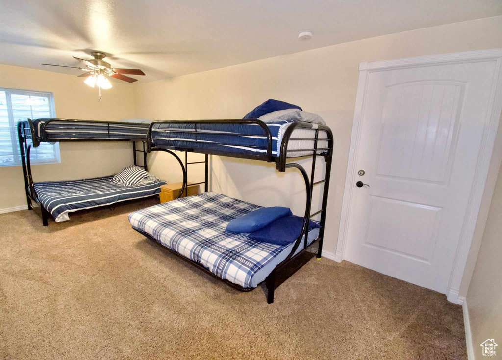 Carpeted bedroom featuring ceiling fan and baseboards