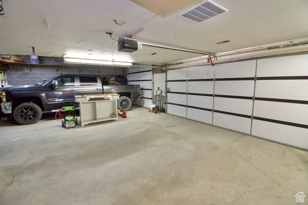 Parking garage featuring a garage door opener and visible vents