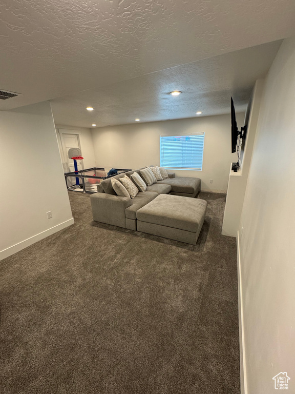 Unfurnished living room featuring baseboards, dark carpet, a textured ceiling, and recessed lighting