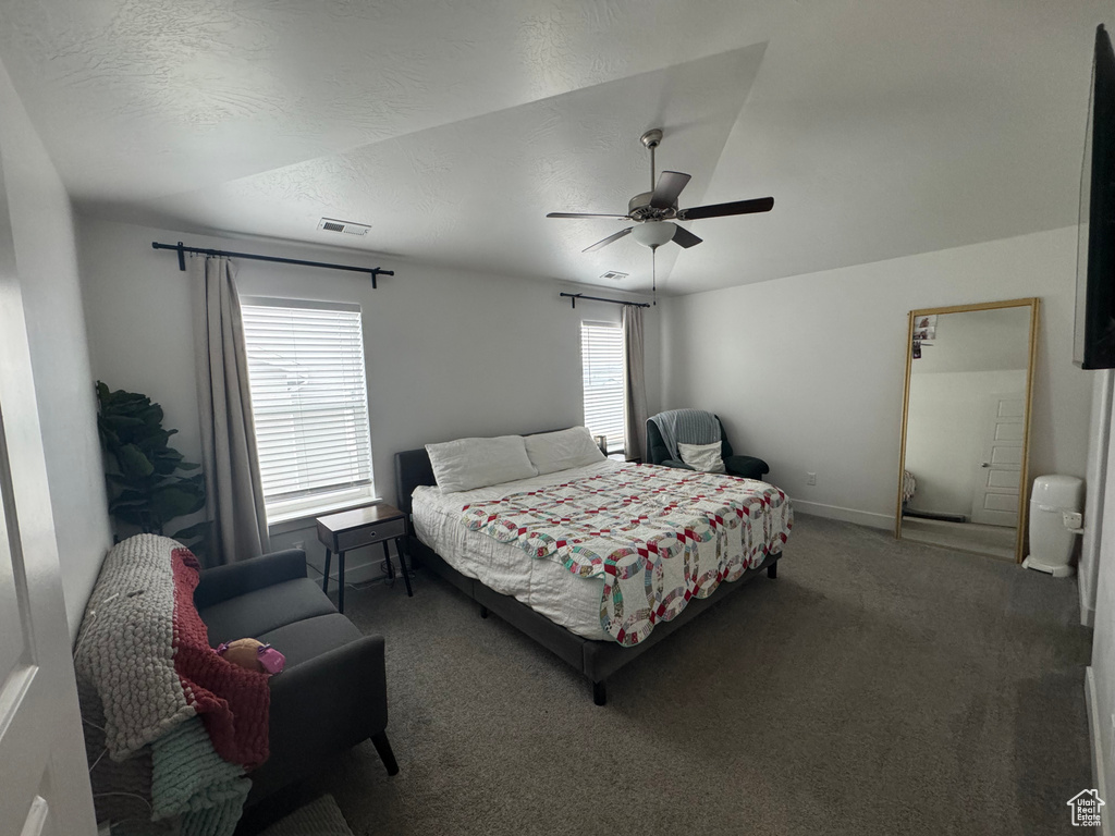 Bedroom featuring a textured ceiling, ceiling fan, visible vents, baseboards, and dark colored carpet
