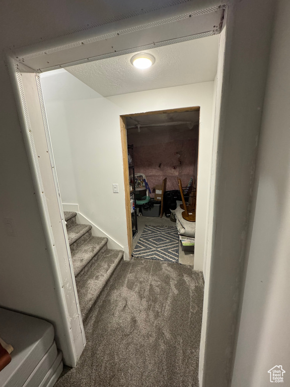Hallway featuring carpet, stairs, and a textured ceiling