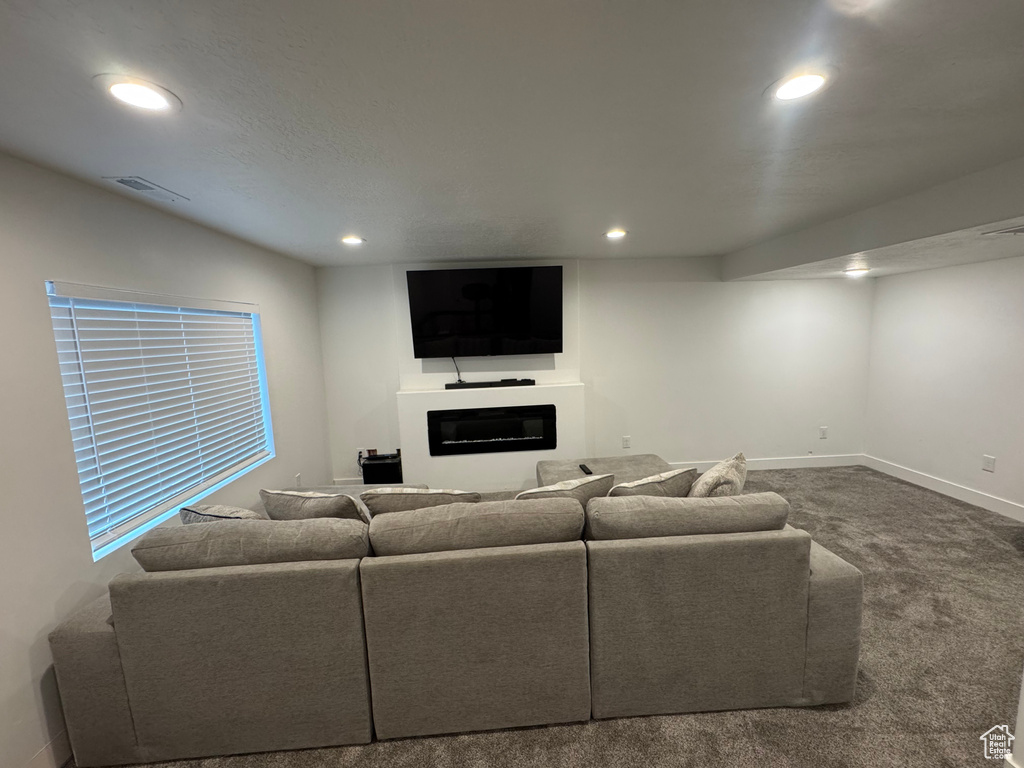 Living room with a glass covered fireplace, visible vents, carpet, and recessed lighting