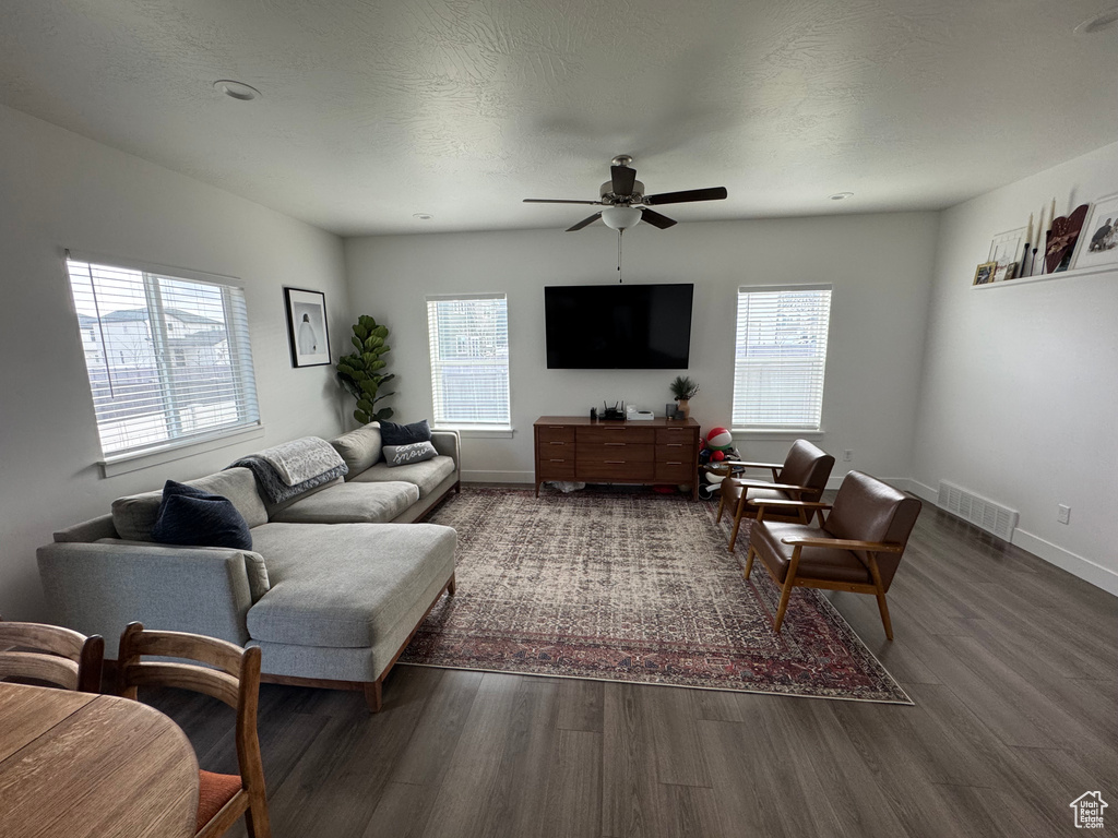 Living area with baseboards, visible vents, dark wood finished floors, and a textured ceiling