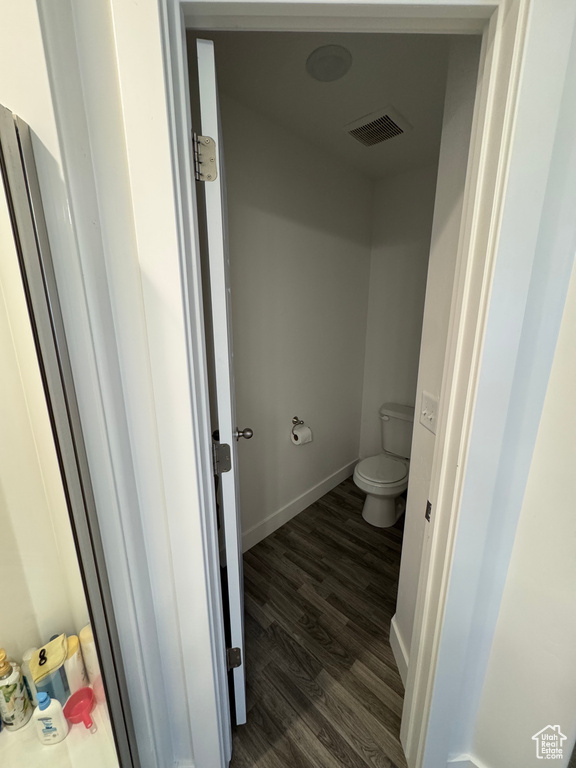 Bathroom featuring toilet, baseboards, visible vents, and wood finished floors
