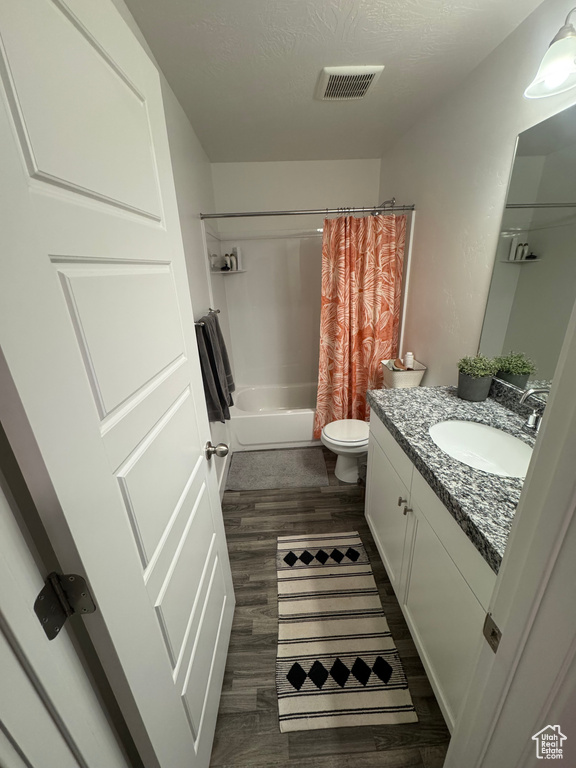 Full bathroom featuring shower / tub combo, visible vents, wood finished floors, a textured ceiling, and vanity