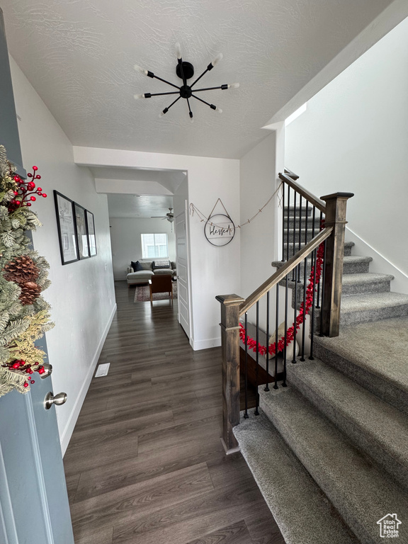 Staircase with a textured ceiling, wood finished floors, a ceiling fan, and baseboards